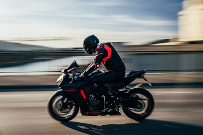 man in black helmet riding black sports bike on road during daytime