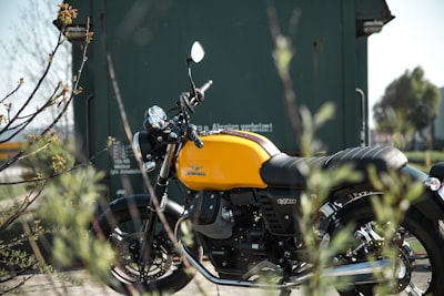 yellow and black standard motorcycle near green wall