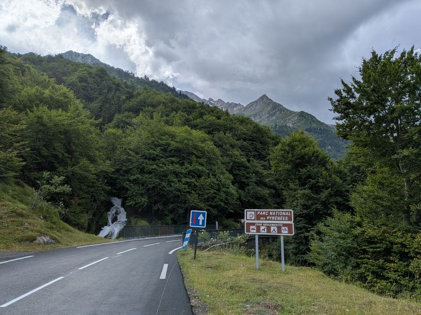 Picturesque road winding through lush greenery in Pyrenees National Park with majestic mountain views.