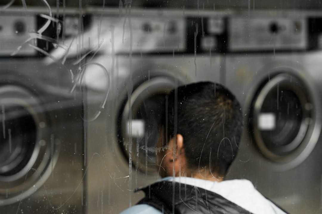 A person looks at washing machines through a wet window